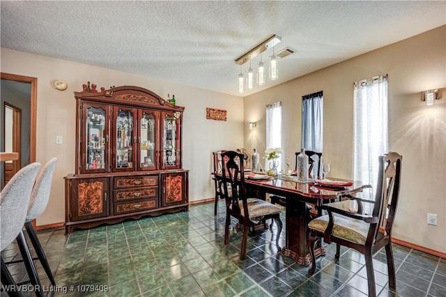 dining area featuring visible vents, a textured ceiling, and baseboards