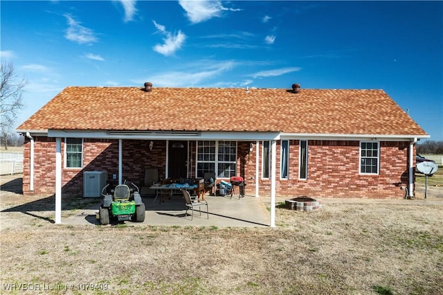 back of house featuring a yard, brick siding, roof with shingles, and a patio area