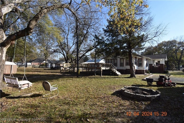 view of yard featuring a deck and an outdoor fire pit