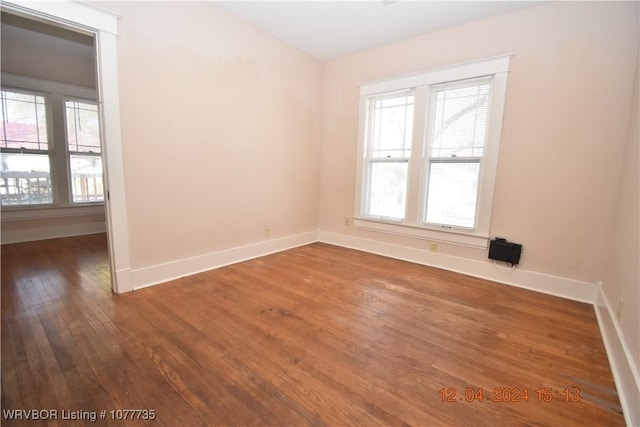 unfurnished room featuring a healthy amount of sunlight and dark hardwood / wood-style floors