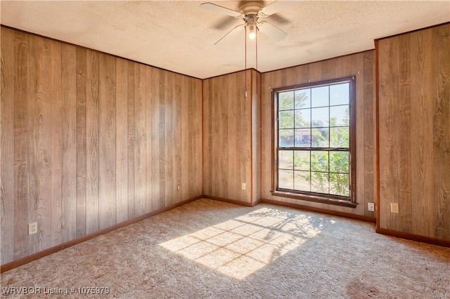 empty room with ceiling fan, carpet floors, and wooden walls