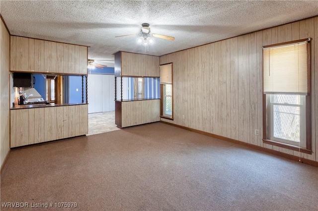 unfurnished room with a textured ceiling, wooden walls, and a healthy amount of sunlight