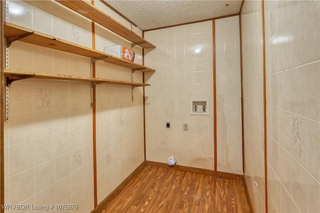 laundry room with electric dryer hookup, hookup for a washing machine, light wood-type flooring, a textured ceiling, and tile walls