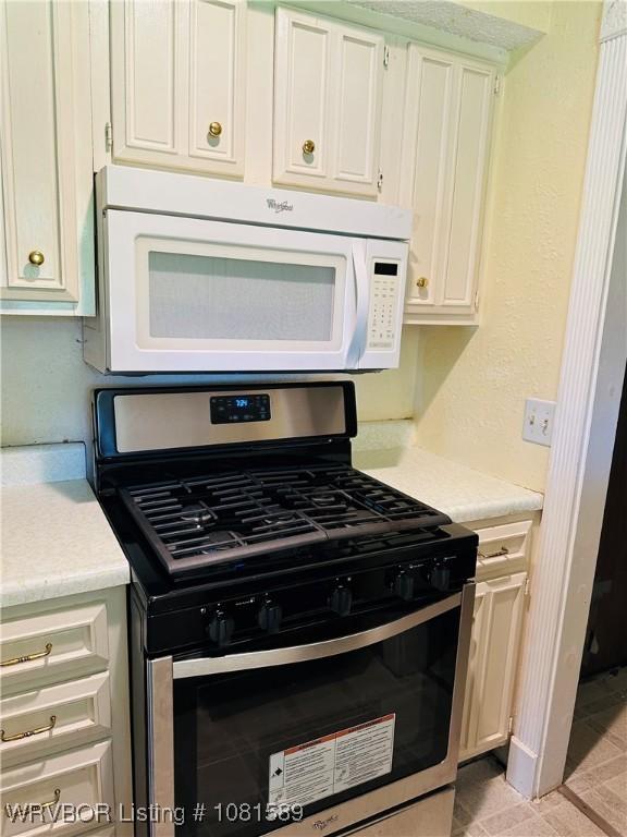1301 9th St, Barling, AR 72923 - kitchen featuring gas range, white microwave, light countertops, and white cabinets