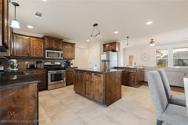 kitchen featuring dark countertops, visible vents, open floor plan, stainless steel appliances, and a sink