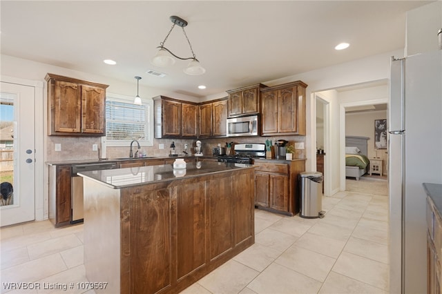 kitchen with visible vents, a sink, stainless steel appliances, tasteful backsplash, and a center island