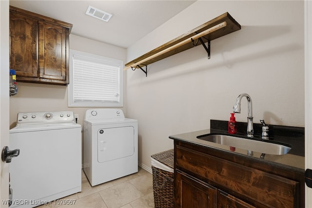 laundry area featuring visible vents, a sink, cabinet space, light tile patterned floors, and washing machine and clothes dryer