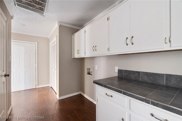 kitchen featuring white cabinets, a textured ceiling, dark hardwood / wood-style floors, and ornamental molding