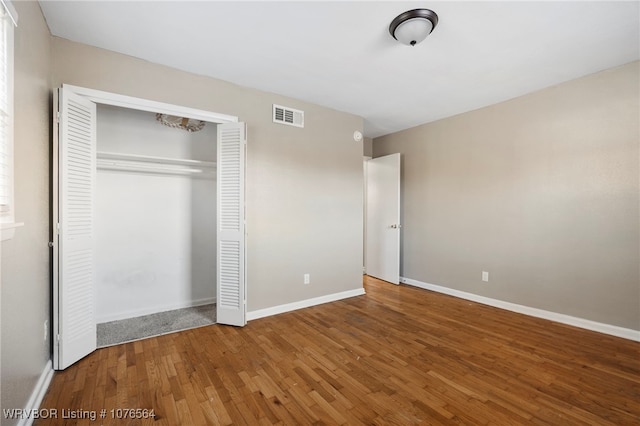 unfurnished bedroom with a closet and hardwood / wood-style floors