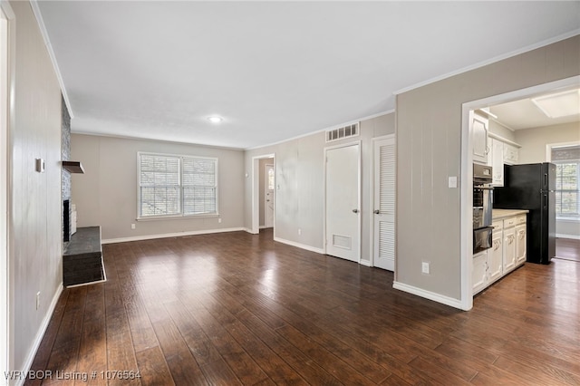 unfurnished living room featuring dark hardwood / wood-style flooring, ornamental molding, and a brick fireplace