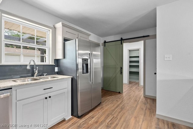 2510 Main St, Charleston, AR 72933 - kitchen with a sink, appliances with stainless steel finishes, a barn door, light wood-type flooring, and light stone countertops