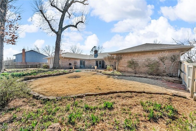 rear view of property with fence and brick siding