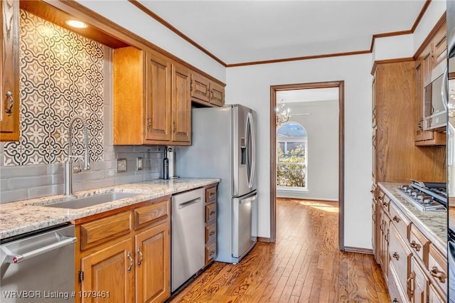 kitchen featuring tasteful backsplash, crown molding, light wood-type flooring, brown cabinets, and appliances with stainless steel finishes