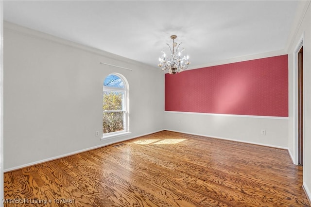 spare room with visible vents, baseboards, an inviting chandelier, and wood finished floors