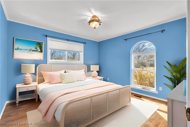 bedroom featuring baseboards, wood finished floors, and ornamental molding