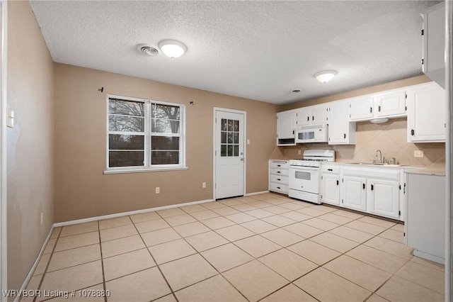 kitchen featuring white cabinetry, sink, decorative backsplash, light tile patterned floors, and white appliances