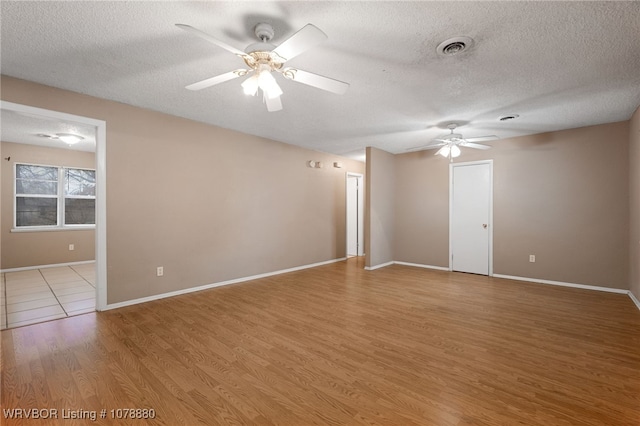 empty room featuring a textured ceiling, ceiling fan, and light wood-type flooring