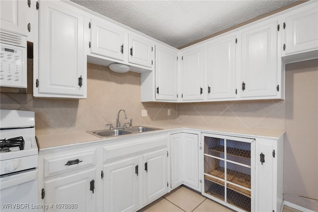 kitchen featuring tasteful backsplash, sink, white appliances, and white cabinets