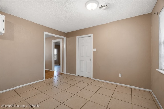 tiled empty room with a wealth of natural light and a textured ceiling