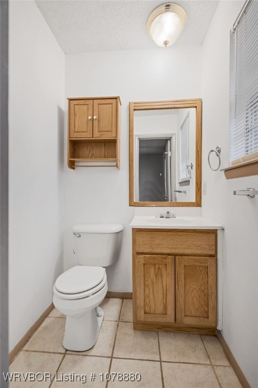 bathroom featuring tile patterned flooring, vanity, a textured ceiling, and toilet