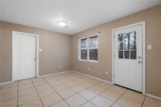 entryway featuring light tile patterned floors and a textured ceiling