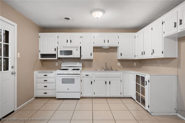 kitchen with light tile patterned flooring, white appliances, sink, and white cabinets