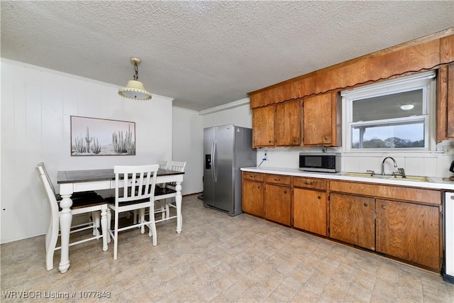 kitchen with appliances with stainless steel finishes, a textured ceiling, hanging light fixtures, and sink