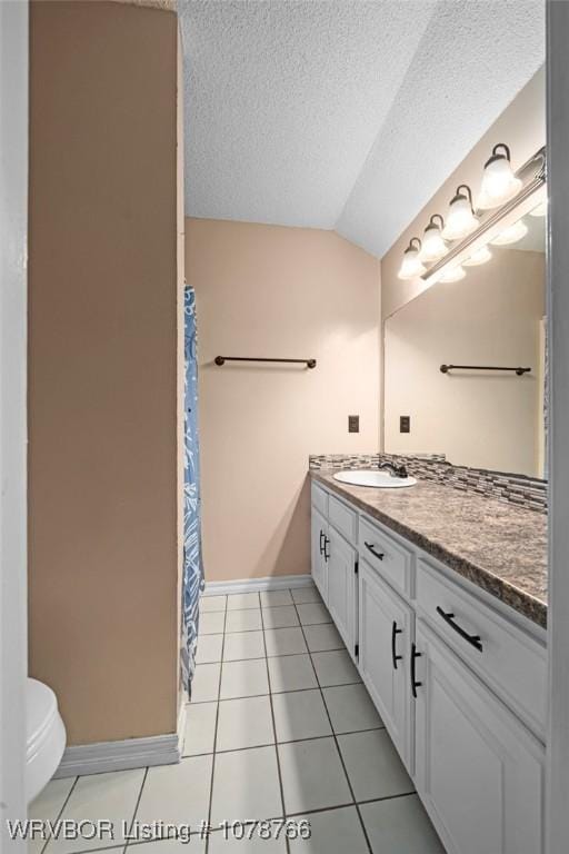 bathroom featuring tile patterned floors, toilet, vaulted ceiling, a textured ceiling, and vanity