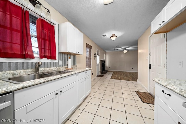 kitchen with light tile patterned flooring, sink, white cabinetry, dishwasher, and ceiling fan