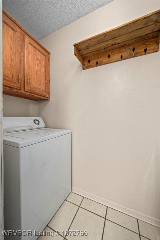 laundry room featuring light tile patterned flooring, cabinets, washer / clothes dryer, and a textured ceiling