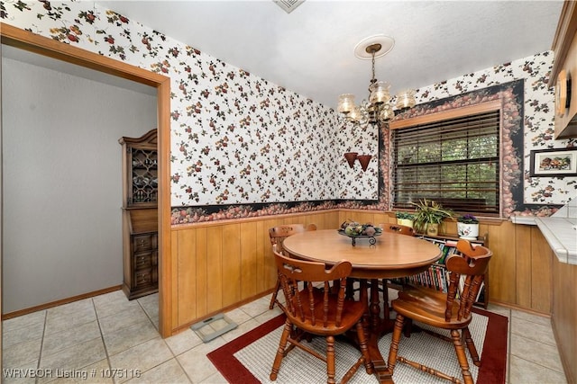 tiled dining area with wooden walls and a notable chandelier