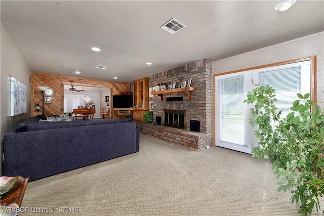 carpeted living room featuring ceiling fan, a fireplace, and wooden walls