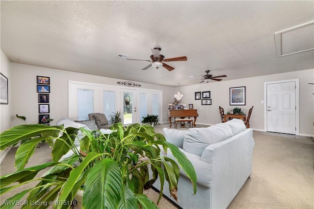 carpeted living room with ceiling fan, a textured ceiling, and french doors