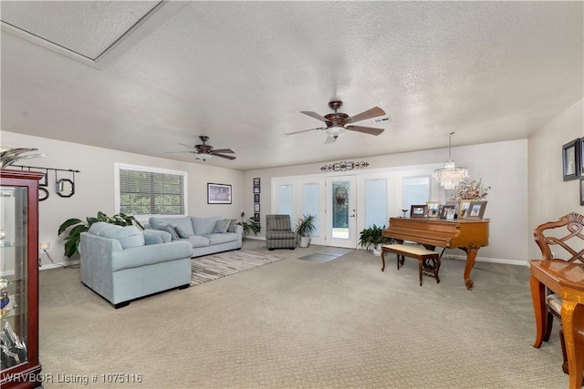 carpeted living room with a textured ceiling, french doors, and ceiling fan with notable chandelier