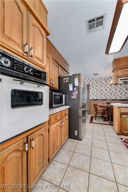 kitchen with decorative backsplash, light tile patterned floors, and stainless steel appliances