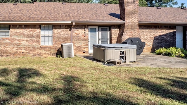 rear view of property with central AC, a patio area, a yard, and a hot tub