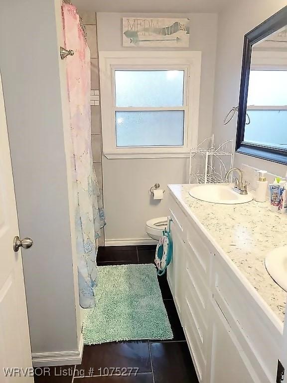 bathroom with tile patterned flooring, vanity, toilet, and a healthy amount of sunlight