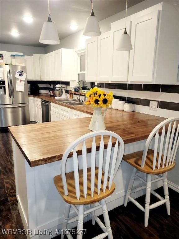 kitchen with butcher block counters, sink, and white cabinets