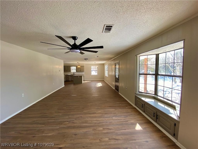 unfurnished living room with ceiling fan with notable chandelier, crown molding, dark wood-type flooring, and a textured ceiling