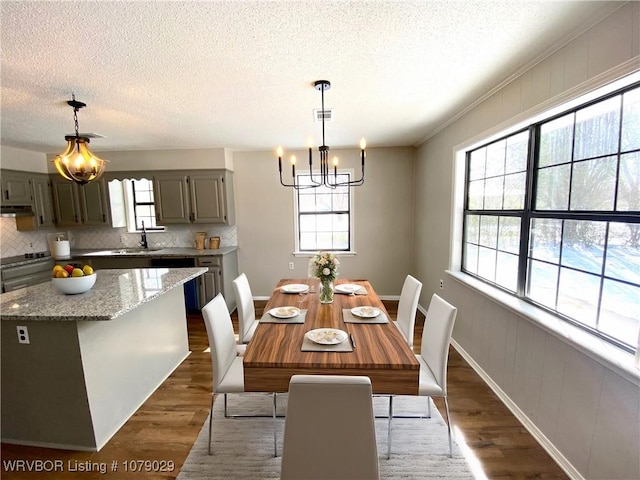 dining space with dark hardwood / wood-style flooring, plenty of natural light, sink, and an inviting chandelier