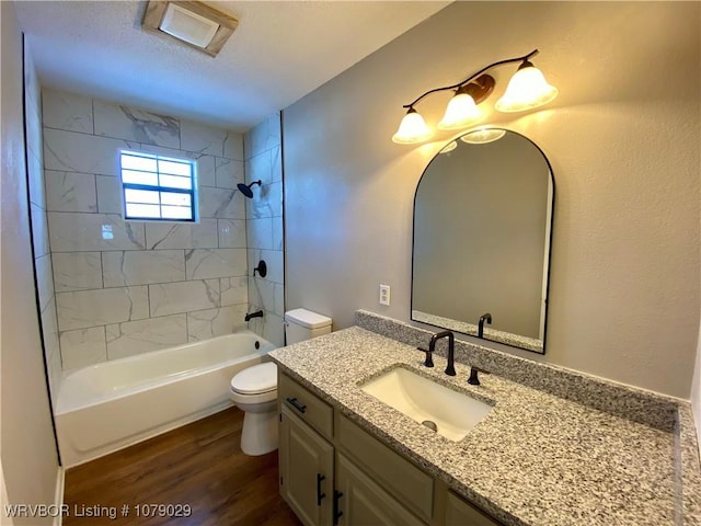 full bathroom with vanity, tiled shower / bath, toilet, and hardwood / wood-style floors