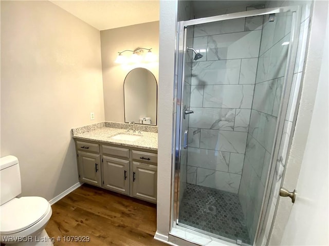 bathroom featuring toilet, wood-type flooring, vanity, and a shower with door