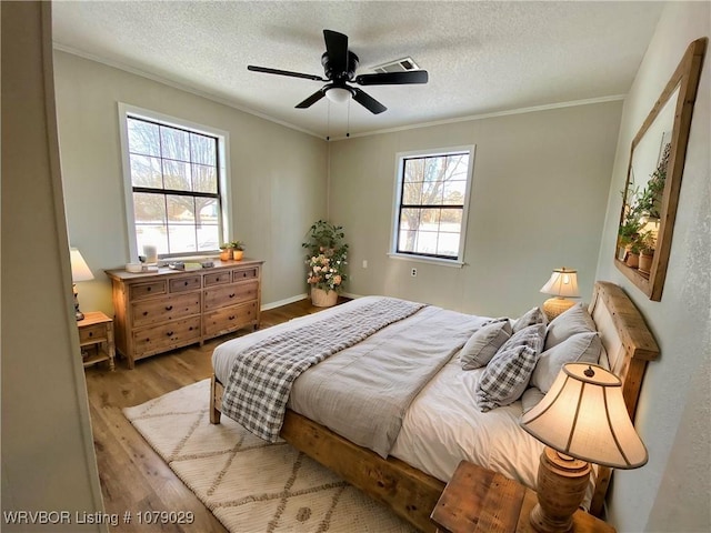 bedroom featuring a textured ceiling, ornamental molding, ceiling fan, and light hardwood / wood-style flooring