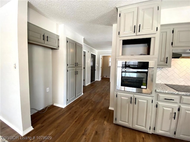 kitchen with backsplash, stainless steel oven, wall chimney range hood, dark wood-type flooring, and black electric stovetop