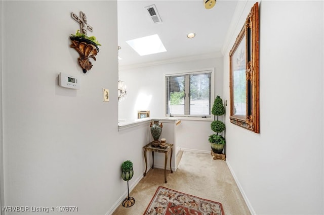 hallway with crown molding, light colored carpet, and a skylight