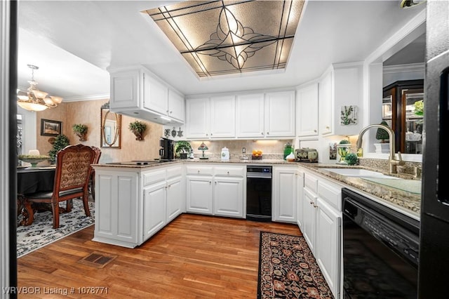 kitchen featuring pendant lighting, sink, light hardwood / wood-style flooring, white cabinetry, and kitchen peninsula