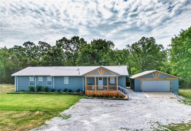 view of front facade with an outbuilding, a garage, covered porch, and a front yard