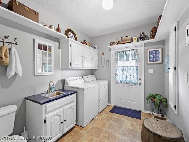laundry room with a textured ceiling, washing machine and clothes dryer, a sink, stone finish flooring, and laundry area