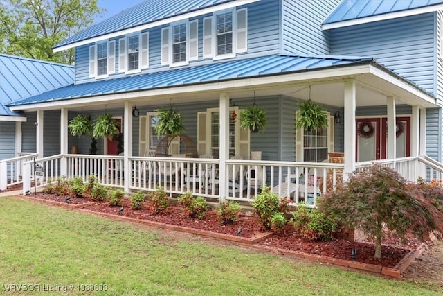 view of front of house featuring a standing seam roof, metal roof, a front lawn, and covered porch
