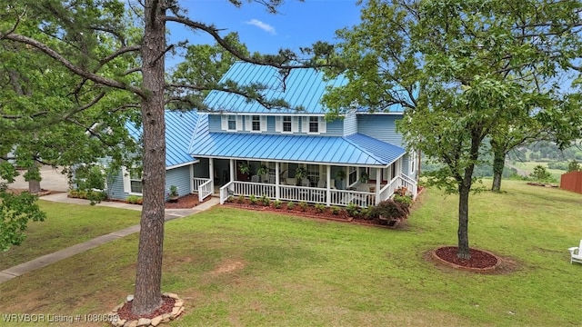 view of front facade featuring covered porch, metal roof, and a front yard